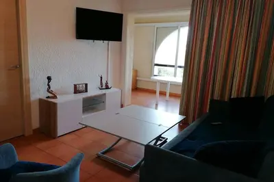 a living room with a couch and a table at Appartement les pieds dans l'eau 300 m plage - 2 piscines in Linguizzetta