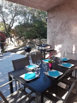 a black table with blue napkins and glasses on a patio at Villa Pinarello climatisée avec piscine chauffée in Sainte-Lucie de Porto-Vecchio