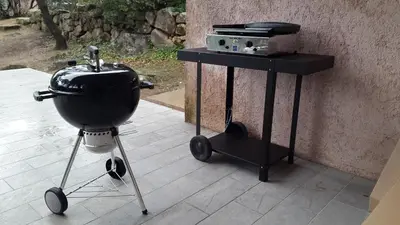 a grill on a stand next to a table at Villa Pinarello climatisée avec piscine chauffée in Sainte-Lucie de Porto-Vecchio