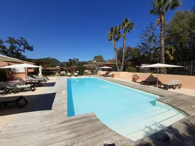 a swimming pool in a resort with tables and chairs at Villa Pinarello climatisée avec piscine chauffée in Sainte-Lucie de Porto-Vecchio