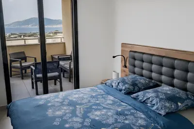 a bedroom with a bed and a view of the ocean at Superbe T2 climatisé, proche plage - belle vue mer in Porticcio