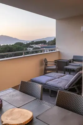 a balcony with chairs and tables and a view at Superbe T2 climatisé, proche plage - belle vue mer in Porticcio
