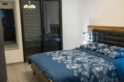 a bed with a blue comforter and pillows on it at Superbe T2 climatisé, proche plage - belle vue mer in Porticcio