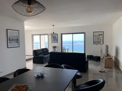 a living room with a couch and a table and chairs at Appartement 140M2 villa cargèse in Cargèse