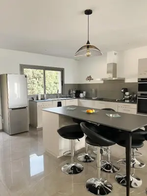 a kitchen with a table with chairs and a refrigerator at Appartement 140M2 villa cargèse in Cargèse