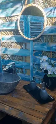 a lamp on a wooden table with a bowl and flowers at Domaine Authentique de Rose in Porto-Vecchio