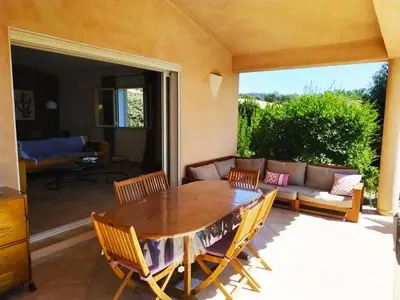 a patio with a wooden table and chairs and a couch at villa Filao Sainte Lucie de Porto vecchio in Sainte-Lucie de Porto-Vecchio
