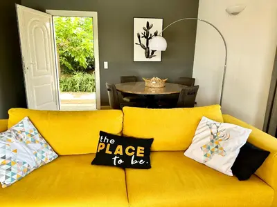 a yellow couch with the place to go pillows on it at villa Filao Sainte Lucie de Porto vecchio in Sainte-Lucie de Porto-Vecchio