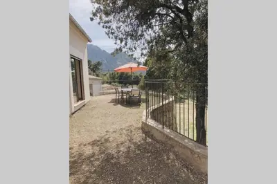 a patio with a table and an umbrella at Villa familiale entre mer et montagne Corse in Soccia