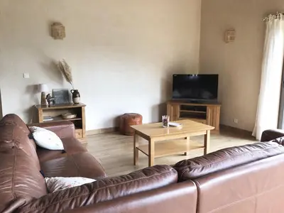 a living room with a leather couch and a table at Villa familiale entre mer et montagne Corse in Soccia