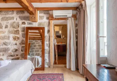 a bedroom with a stone wall with a bed and a mirror at Auberge U n'Antru Versu in San-Gavino-di-Carbini