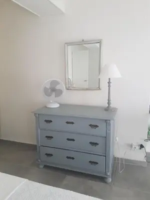 a blue dresser with a lamp and a mirror at Charmant 2 pièces en plein coeur du village in Cargèse