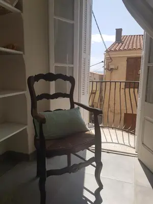 a chair with a pillow sitting on a balcony at Charmant 2 pièces en plein coeur du village in Cargèse
