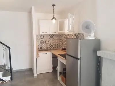 a kitchen with a refrigerator and white cabinets at Charmant 2 pièces en plein coeur du village in Cargèse