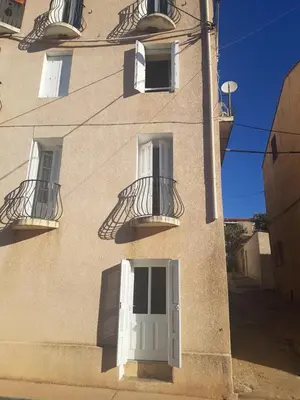 a building with two balconies and a white door at Charmant 2 pièces en plein coeur du village in Cargèse