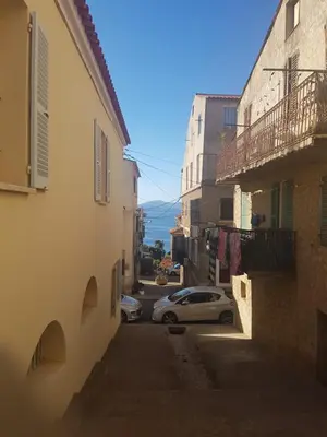 an alley with buildings and a car parked on the street at Charmant 2 pièces en plein coeur du village in Cargèse