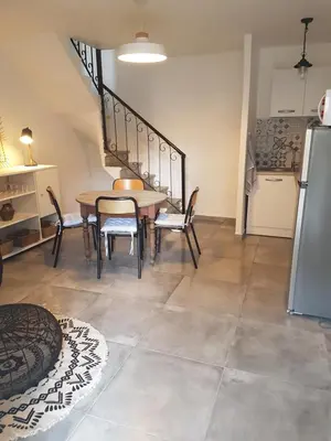a dining room with a table and chairs and a refrigerator at Charmant 2 pièces en plein coeur du village in Cargèse