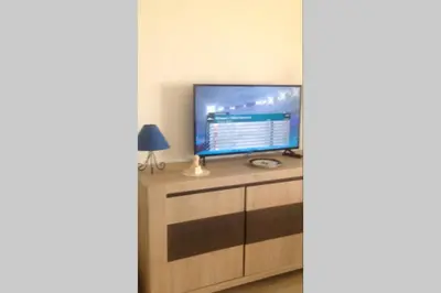 a television sitting on top of a wooden cabinet at T2 Sanguinaires calme et cosy, entre mer et maquis in Ajaccio