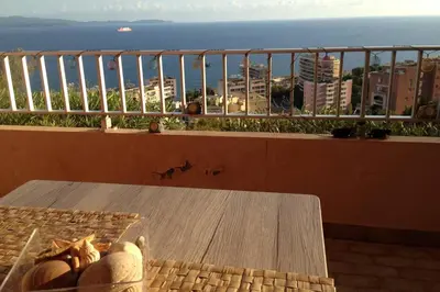 a table on a balcony with a view of the ocean at T2 Sanguinaires calme et cosy, entre mer et maquis in Ajaccio