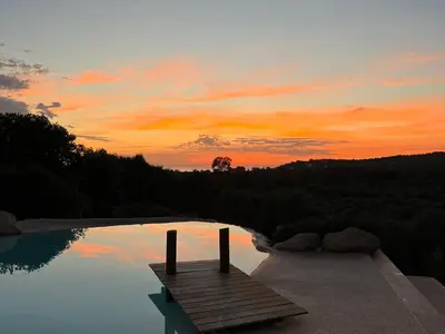 a sunset over a pool with a wooden dock at Casa Lagone - Villa Luxe avec Piscine et Superbe Vue in Cargèse