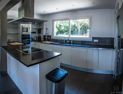 a kitchen with white cabinets and a black counter top at Casa Lagone - Villa Luxe avec Piscine et Superbe Vue in Cargèse