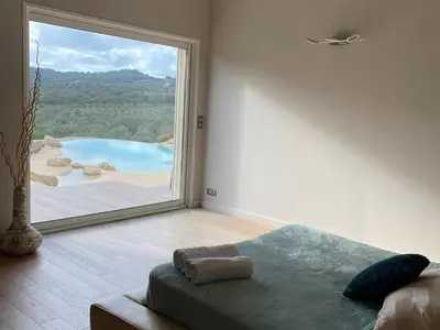 a bedroom with a large window with a view of a pool at Casa Lagone - Villa Luxe avec Piscine et Superbe Vue in Cargèse