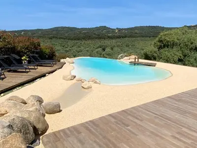 a swimming pool with rocks and a wooden deck at Casa Lagone - Villa Luxe avec Piscine et Superbe Vue in Cargèse