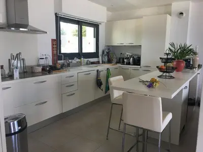 a kitchen with white cabinets and a table with chairs at VUE MAGNIFIQUE SUR BAIE AJACCIO in Porticcio