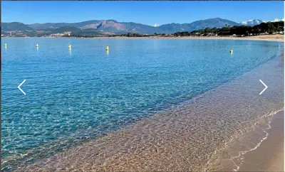 a beach with blue water and mountains in the background at VUE MAGNIFIQUE SUR BAIE AJACCIO in Porticcio