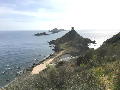 a lighthouse on a hill next to the ocean at VUE MAGNIFIQUE SUR BAIE AJACCIO in Porticcio
