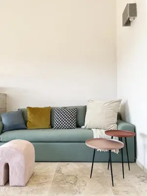 a living room with a green couch and two tables at A Casa di Santa Giulia in Porto-Vecchio