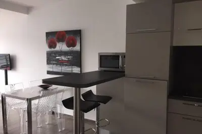 a kitchen with a black counter and a table and chairs at Appartement T2 terrasse vue mer à 180 in Propriano