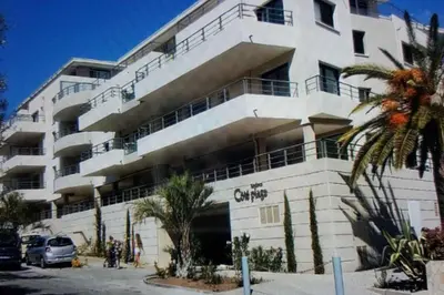 a large white building with cars parked in front of it at Appartement T2 terrasse vue mer à 180 in Propriano