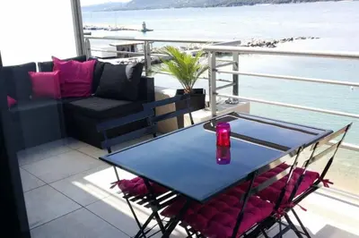 a table and chairs on a balcony with a view of the water at Appartement T2 terrasse vue mer à 180 in Propriano