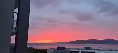 a sunset over the water with a building at Les Rivages De Stagnola - Vue Mer et Plages à Pied in Pietrosella