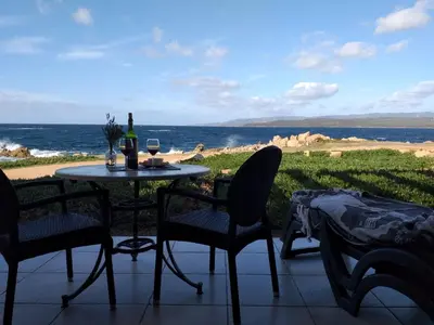a table with a bottle of wine and chairs on a patio at Residences La Tonnara in Bonifacio