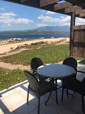 a table and chairs on a porch with a view of the beach at Residences La Tonnara in Bonifacio