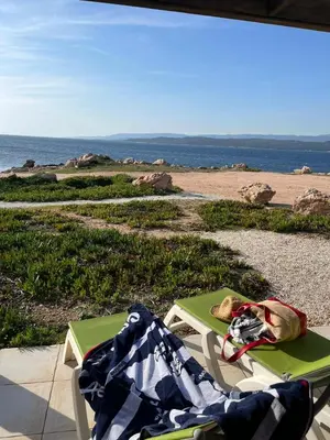 a table and chairs on a beach with the ocean at Residences La Tonnara in Bonifacio
