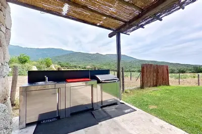 an outdoor kitchen with a view of the mountains at Bergeries de l'Argiale - ARGHJALE - hôtel in Figari