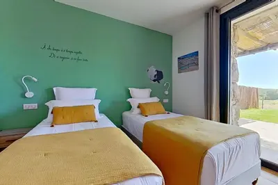 two beds in a room with a green wall at Bergeries de l'Argiale - ARGHJALE - hôtel in Figari