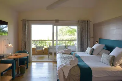 a bedroom with a bed and a balcony with a table at Hôtel Alivi Di Santa Giulia in Porto-Vecchio