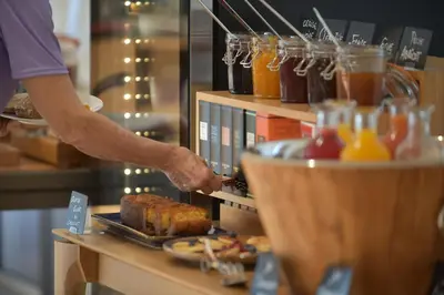 a person preparing food on a counter in a store at Hôtel Alivi Di Santa Giulia in Porto-Vecchio