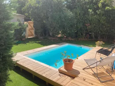 a swimming pool on a wooden deck next to a yard at Maison pieds dans l eau avec piscine et clim in Linguizzetta