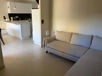 a living room with a couch and a kitchen at Maison pieds dans l eau avec piscine et clim in Linguizzetta