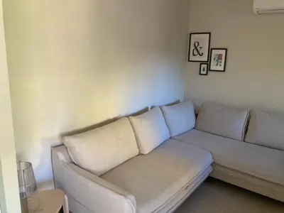 a living room with a couch in the corner at Maison pieds dans l eau avec piscine et clim in Linguizzetta