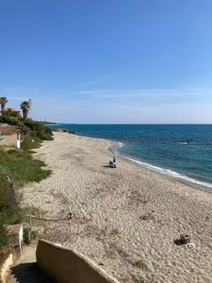 a person sitting on a beach near the ocean at Maison pieds dans l eau avec piscine et clim in Linguizzetta