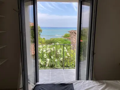 a bedroom with a view of the ocean from a window at Maison pieds dans l eau avec piscine et clim in Linguizzetta