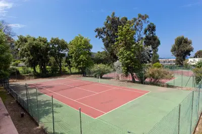 a tennis court with a net and trees on it at Residence Club Marina Viva in Porticcio