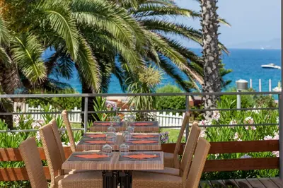 a wooden table with chairs and the ocean in the background at Residence Club Marina Viva in Porticcio