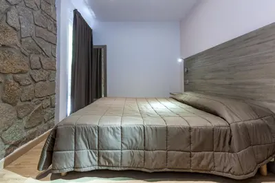 a bedroom with a large bed in a stone wall at Residence Club Marina Viva in Porticcio